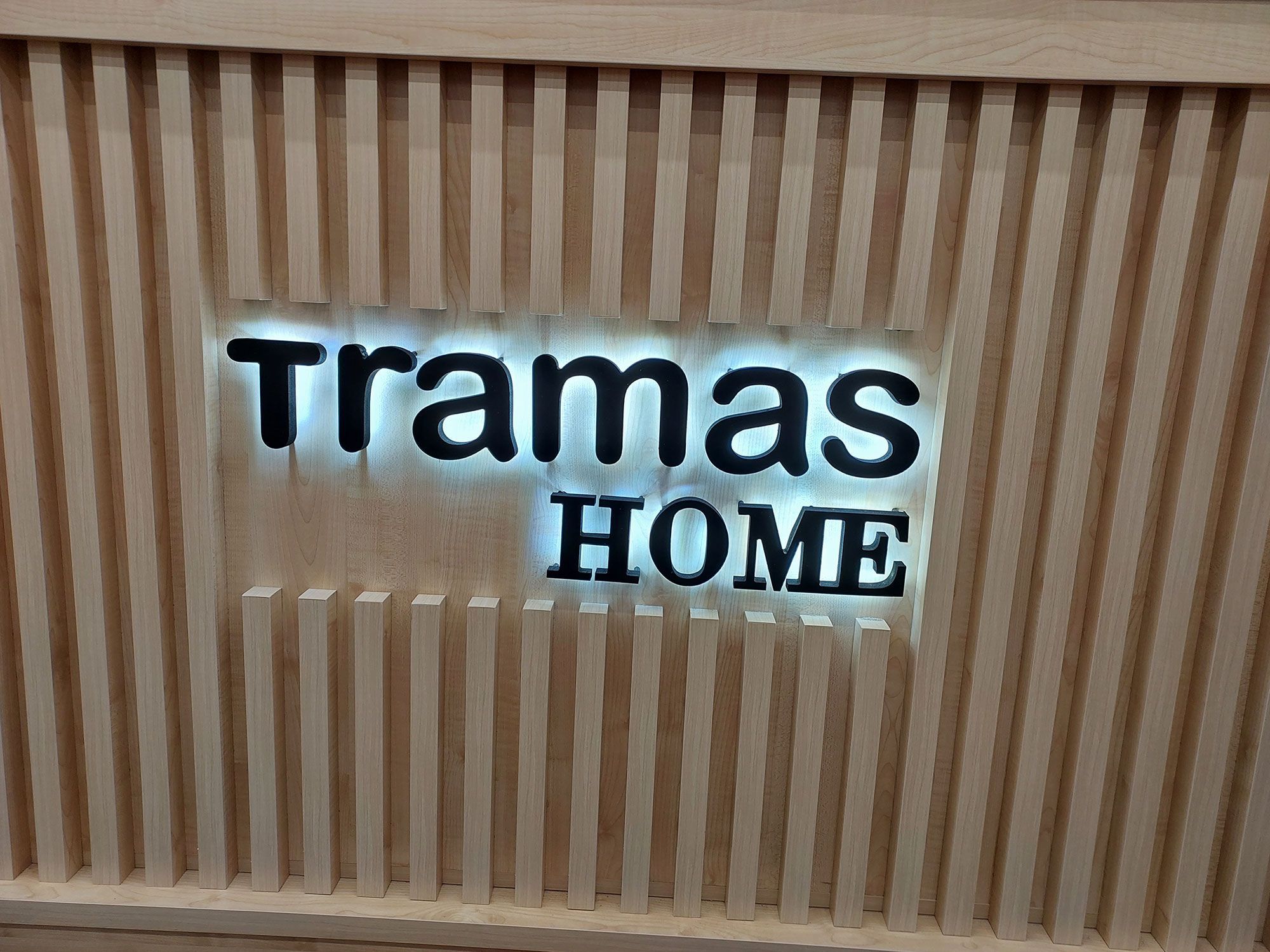 Letras corpóreas retroiluminadas de Tramas Home sobre revestimiento de madera